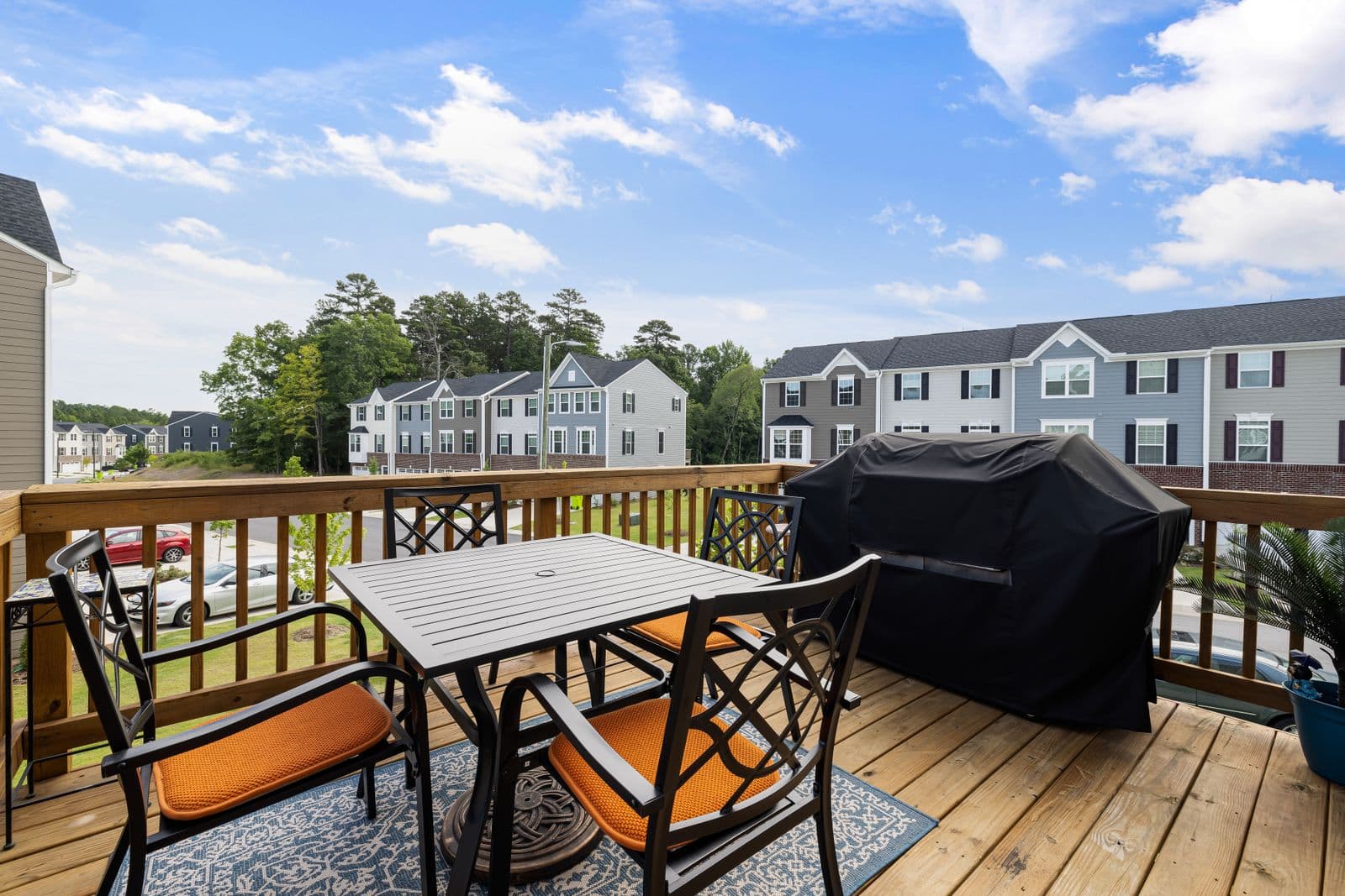 Wood deck with table, chairs and grill overlooking a yard
