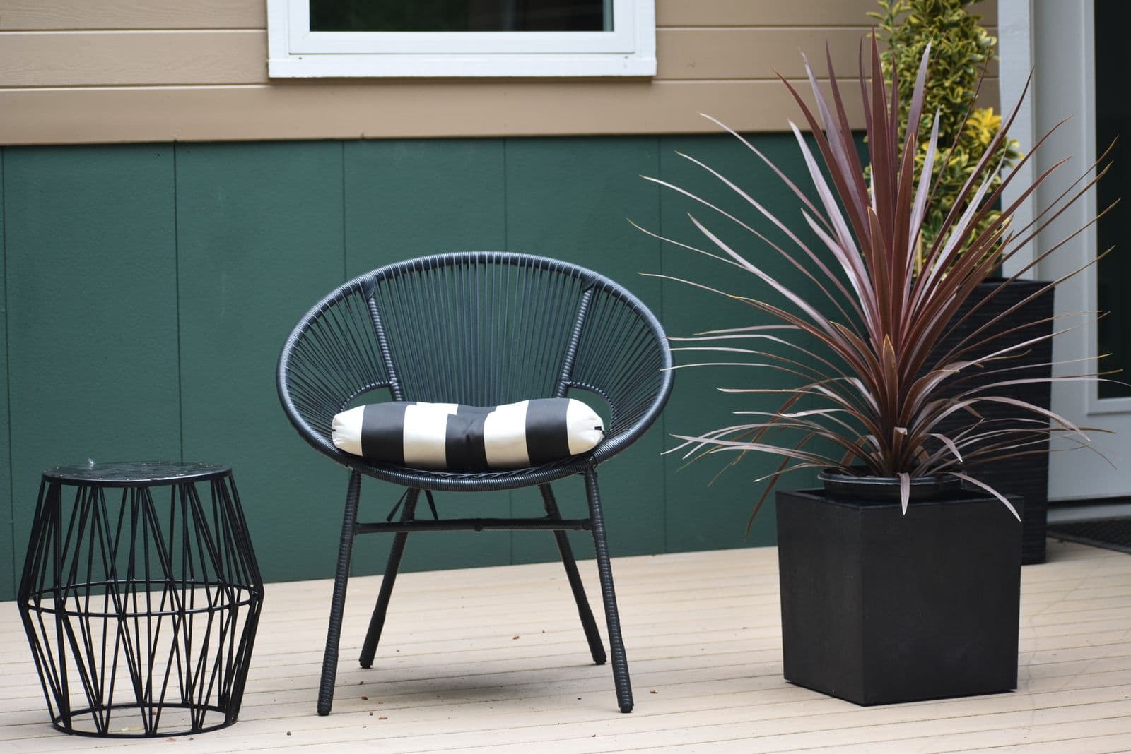 Light gray deck with a chair, side table and potted plant