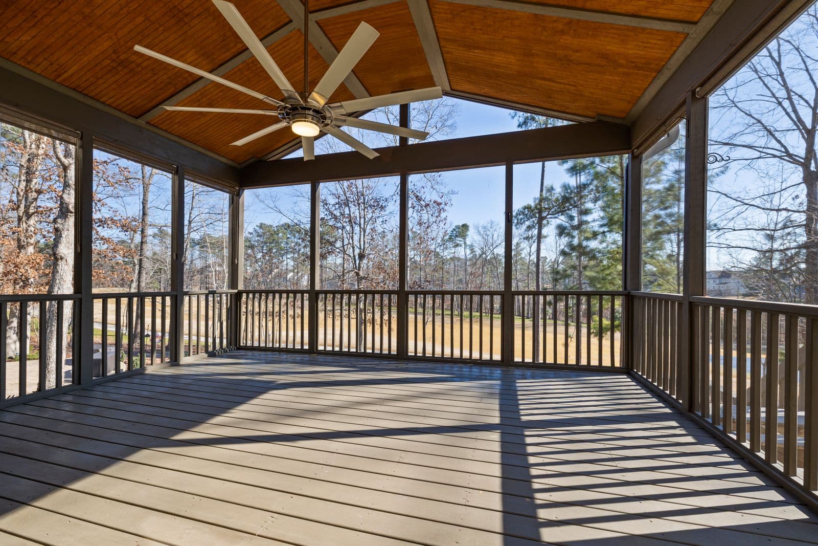 Screened porch with a ceiling fan and a view of trees